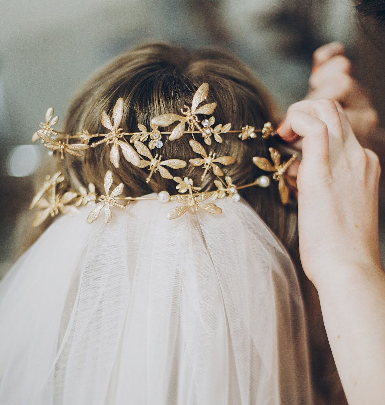 Hair stylish putting on stylish bride golden tiara with butterflies