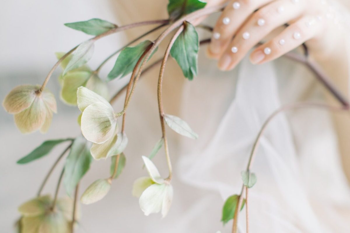 The bride in a veil holding a sprig of hellebore.